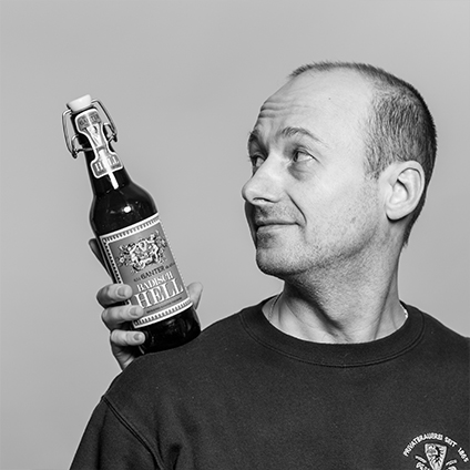 Ein schwarz-weiß Bild eines Mannes, der ein Ganter Helles Bier auf den trägt