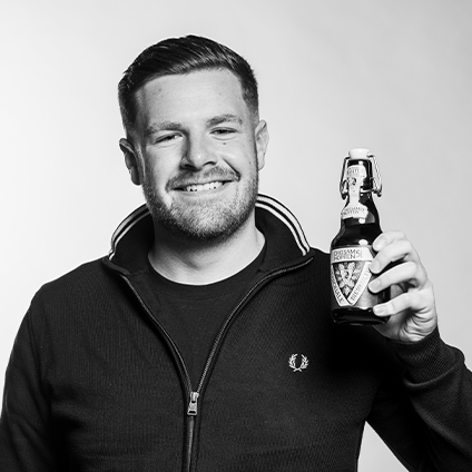 Ein Schwarz-Weiß-Foto eines Mannes mit einer Ganter Dreisamhopfen Bierflasche